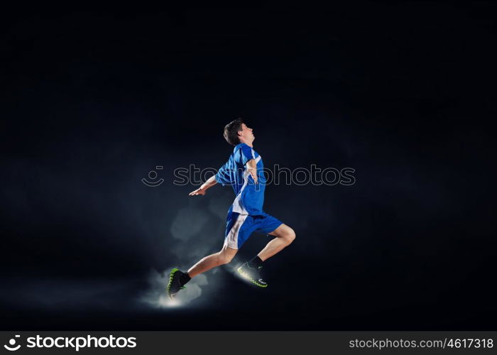 At full speed. Running man in blue sport wear on black background