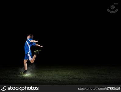 At full speed. Running man in blue sport wear on black background