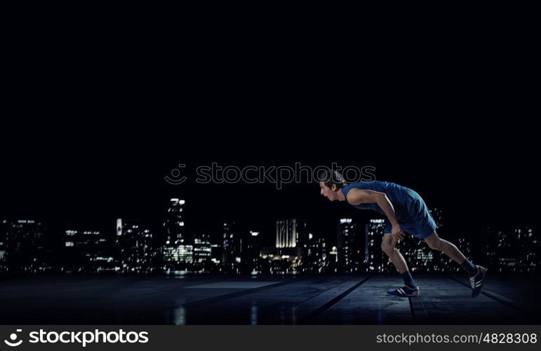 At full speed. Running man in blue sport wear on black background