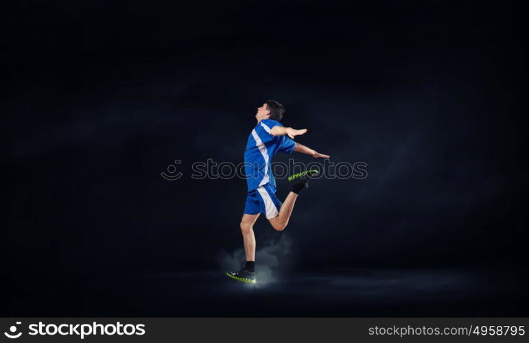 At full speed. Running man in blue sport wear on black background