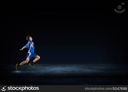 At full speed. Running man in blue sport wear on black background