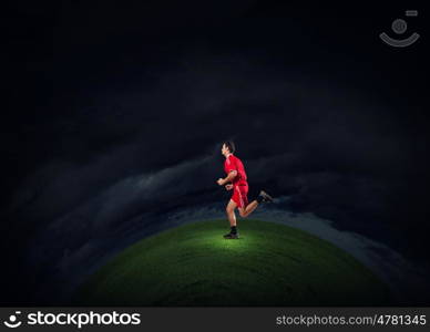 At full speed. Running man in red sport wear on dark background