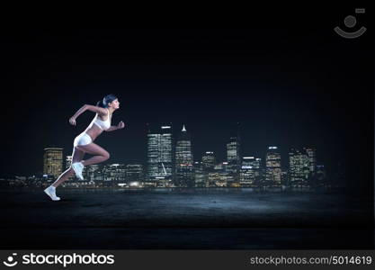 At full speed. Young woman athlete running fast on dark background