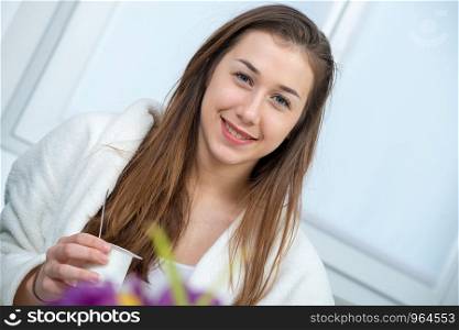 at morning, a young and smiling woman eating yogurt