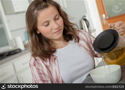 at morning, teenage girl is drinking tea in a bowl