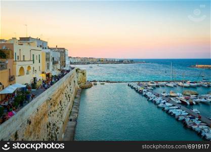 At peak of turistic season, the turist crowd is walking at sunset on the road from the new to the old side of Otranto town