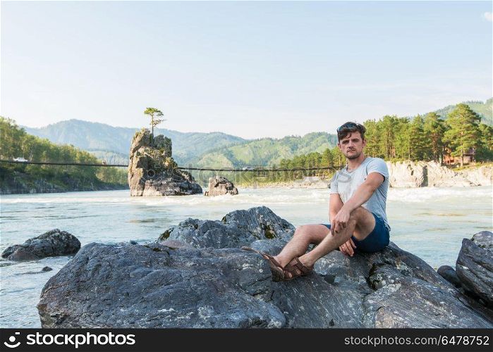 at riverbank of mountain river. Young man spending time at riverbank of mountain river