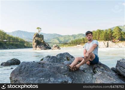 at riverbank of mountain river. Young man spending time at riverbank of mountain river