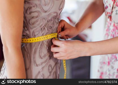 At tailors studio. Pretty dressmaker at work making measures of client