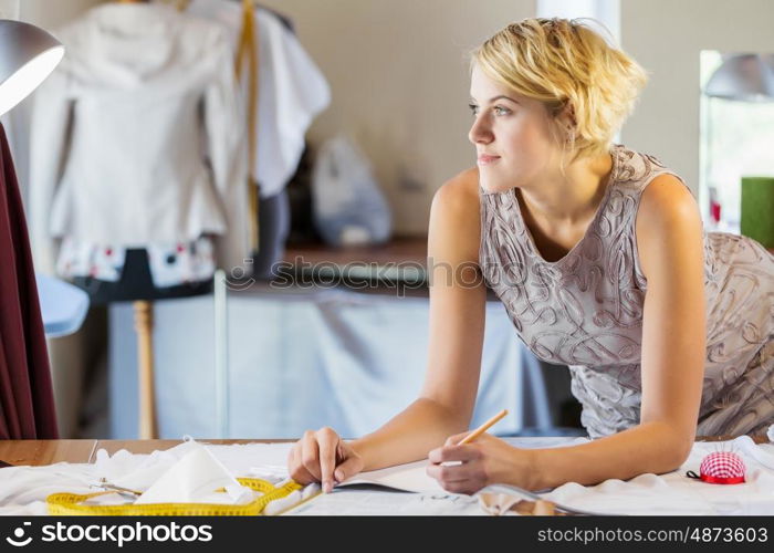 At tailors studio. Pretty dressmaker at work making patterns of fabric