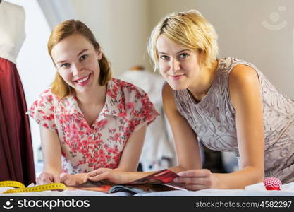 At tailors studio. Two attractive women at dressmakers choosing design