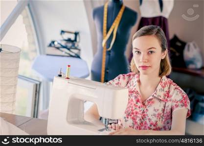 At tailors studio. Young woman dressmaker working on sewing machine