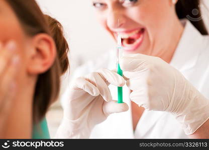 At the dentist - a female patient is getting ready to receive a anesthetization syringe, the nurse has a very disturbing diabolic smile (focus on hand of nurse)