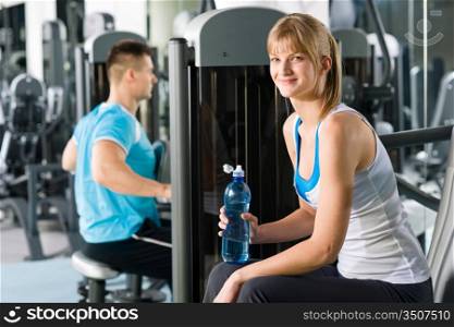 At the fitness center young woman relax on exercise machine