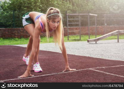 at the start. A young beauty athletic woman in sportswear preparing for running at outdoor early morning. Healthy lifestyle.