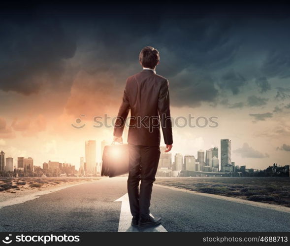 At the start of long way. Back view of businessman standing on road and looking far away