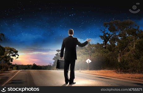 At the start of long way. Back view of businessman standing on road and looking far away