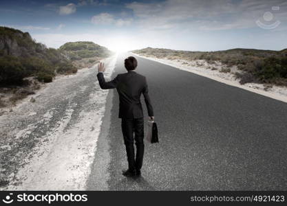 At the start of long way. Back view of businessman standing on road and looking far away