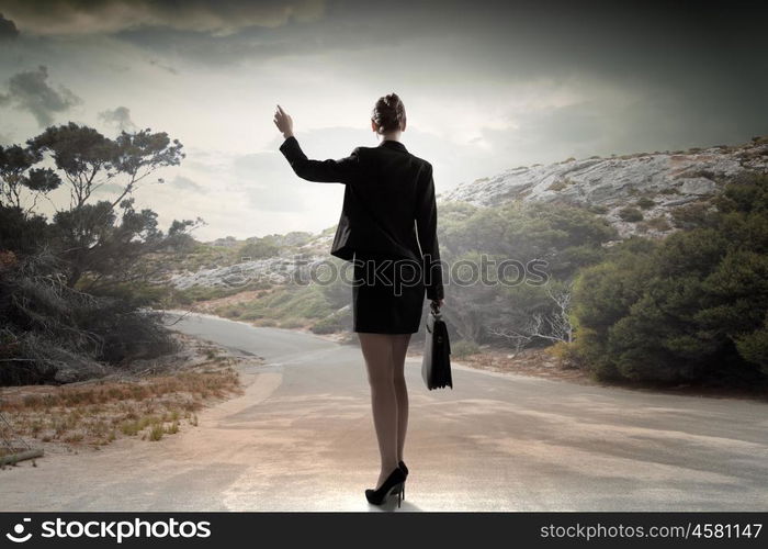 At the start of long way. Back view of businesswoman standing on road and looking far away