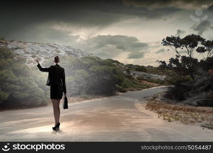 At the start of long way. Back view of businesswoman standing on road and looking far away