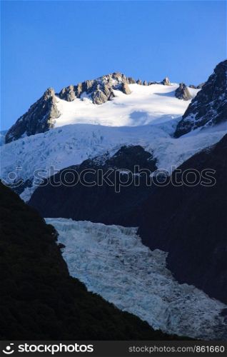 At the summit arises Franz Josef glacier and blue sky in New Zealand