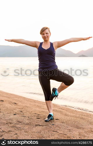 athlete balances on one foot on the beach