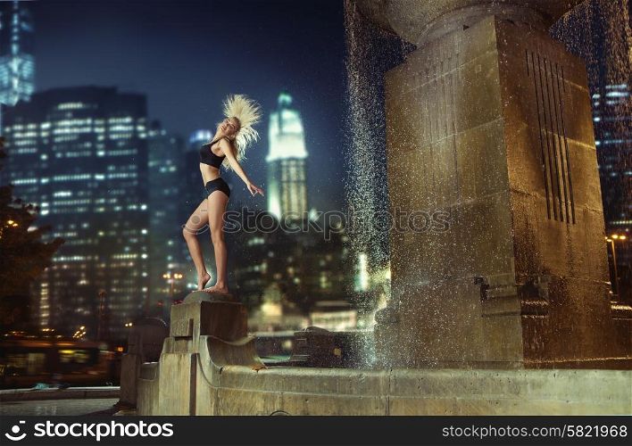 Athlete dancing on the fountain in the night