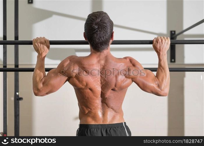 Athlete doing pull-ups at the gym. Handsome man doing functional training. High quality photo.. Athlete doing pull-ups at the gym. Handsome man doing functional training.