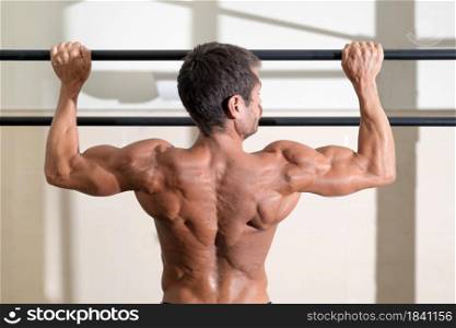 Athlete doing pull-ups at the gym. Handsome man doing functional training. High quality photo.. Athlete doing pull-ups at the gym. Handsome man doing functional training.