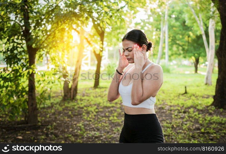 Athlete girl with migraine in a park. Young female runner rubbing her head with migraine in a park. Runner woman with headache and fatigue in the park, Runner woman with headache in a park