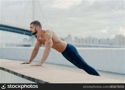 Athlete guy stands in plank pose does push up exercise outdoor breathes fresh air has strong body and naked torso motivation in staying fit and healthy leads active lifestyle. Sports training concept