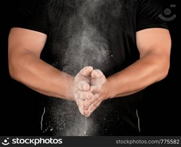 athlete in black clothes clapping, white talc magnesium fly away, preparing to sporting events
