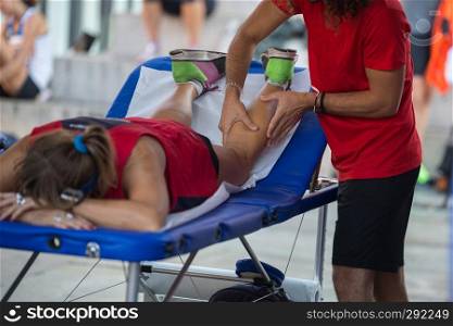 Athlete lying on a Bed while having Legs Massaged after a Physical Sports Workout.. Athlete lying on a Bed while having Legs Massaged after a Physical Sports Workout