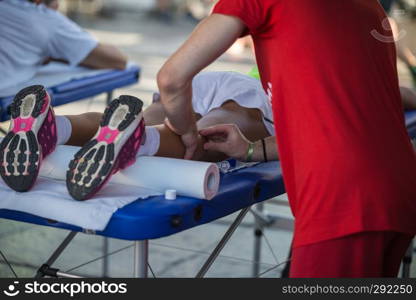 Athlete lying on a Bed while having Legs Massaged after a Physical Sports Workout.. Athlete lying on a Bed while having Legs Massaged after a Physical Sports Workout