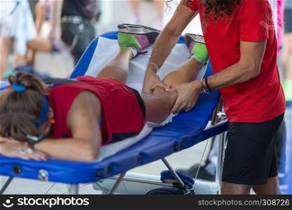 Athlete lying on a Bed while having Legs Massaged after a Physical Sports Workout.. Athlete lying on a Bed while having Legs Massaged after a Physical Sports Workout