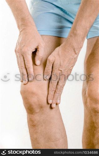 Athlete man massaging a painful quadriceps and the knee after a sport accident. It could be a quadriceps tendinopathy, a muscle elongation, a medial meniscus tears or bursitis