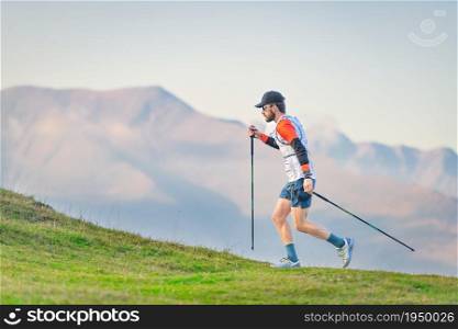 Athlete practicing Nordic walking on hilly meadows