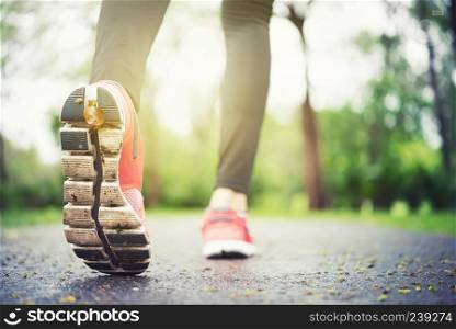 Athlete runner feet running on the road closeup on shoe. Jogger fitness shoe with free space background. Runner jogging outdoors in city.