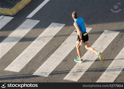 Athlete running man. Male runner passing crosswalk