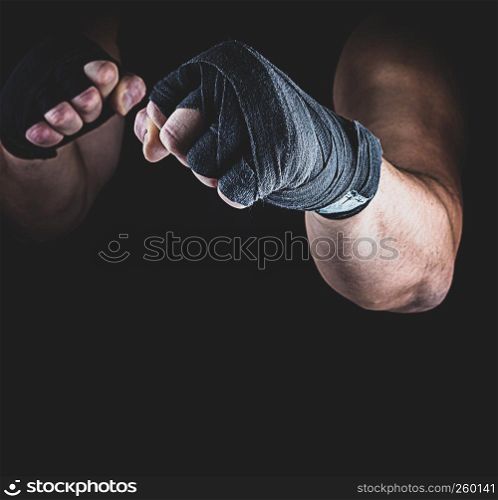 athlete stands in a fighting stance, his hands wrapped in black textile bandage