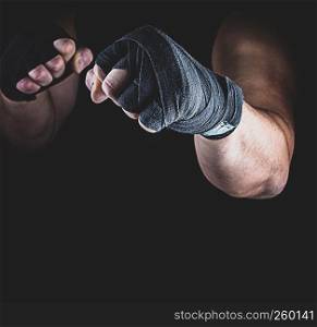 athlete stands in a fighting stance, his hands wrapped in black textile bandage