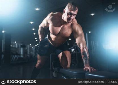 Athlete with muscular body lifting dumbbells, bodybuilding workout in sport gym. Weightlifting training