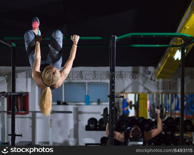 athlete woman doing abs exercises hanging upside down on horizontal bar ...