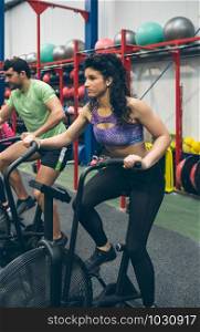 Athlete woman doing air bike at the gym. Sportswoman doing air bike at the gym
