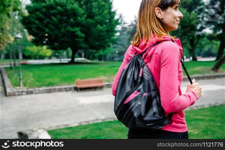 Athlete woman with backpack going to the gym outdoors