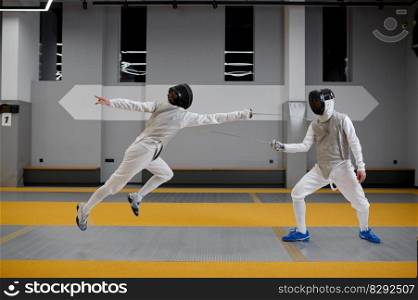 Athletes in uniforms and protective helmet mask fighting duel with rapiers. Swordsmanship competition concept. Athletes in uniforms and protective helmet mask fighting duel with rapiers