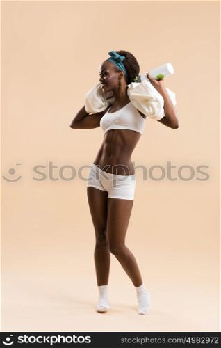 Athletic african girl with a bottle of water and towel