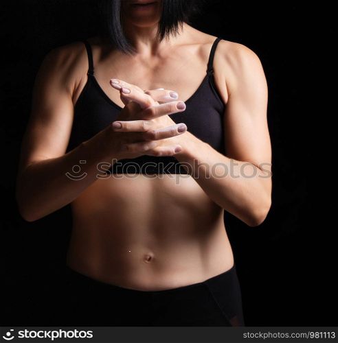athletic arms with veins and the muscular torso of a young girl with black hair, she rubs white magnesia into her skin, low key