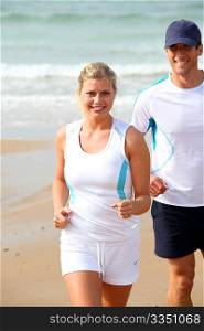 Athletic couple running by the sea in summer