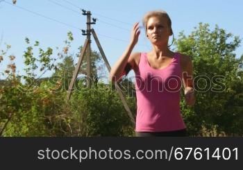 Athletic fit young woman jogging on the road during outdoor workout